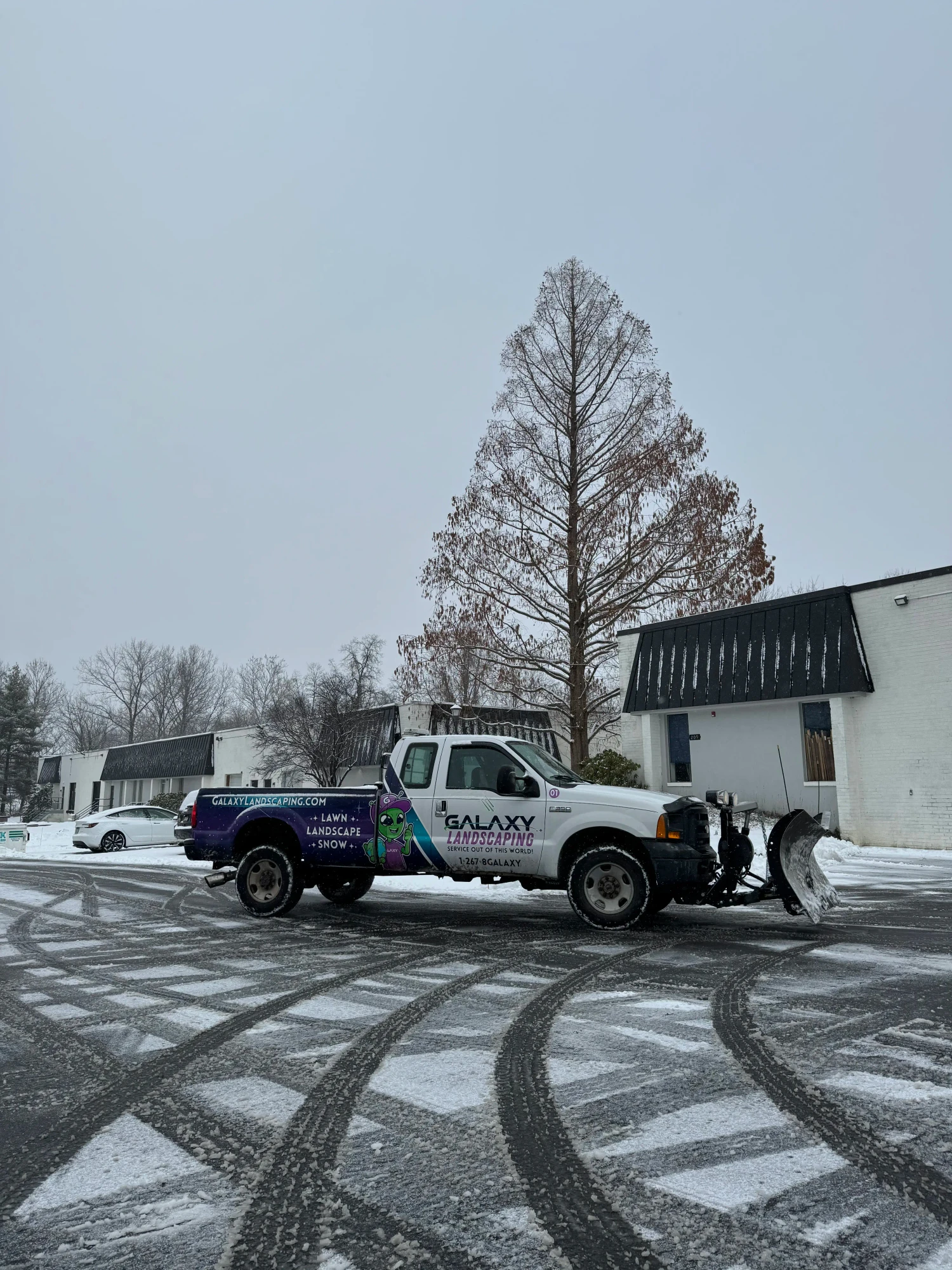 Galaxy Landscaping snow plow truck actively clearing snow from a commercial lot in Bucks County.